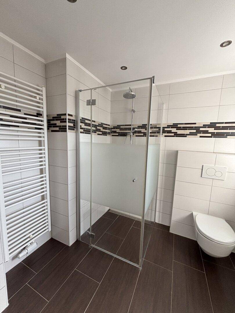 Zeitgemäßes Badezimmer mit großer begehbarer Dusche und praktischem Handtuchheizkörper.