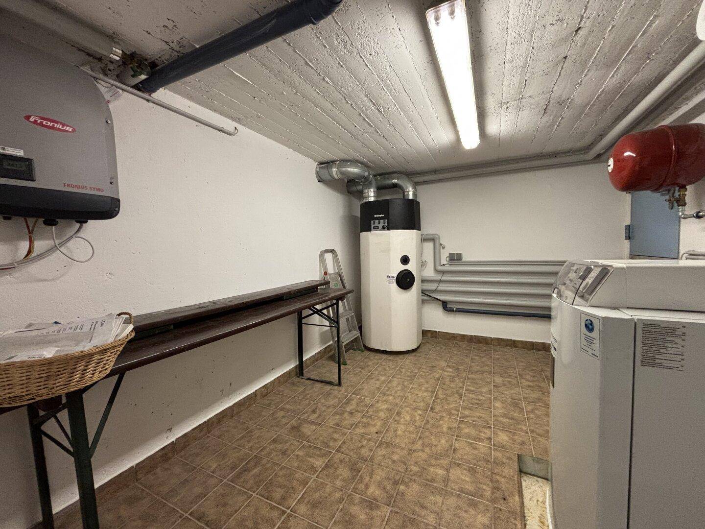 Hauswirtschaftsraum im Keller mit Heizungsanlage, Waschmaschine und praktischer Arbeitsfläche.