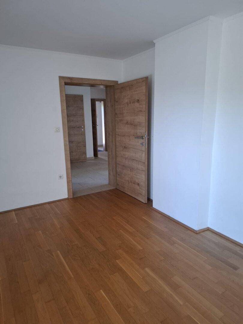 Leerer Raum mit hellem Parkettboden und Holztüren, bereit zur individuellen Gestaltung.