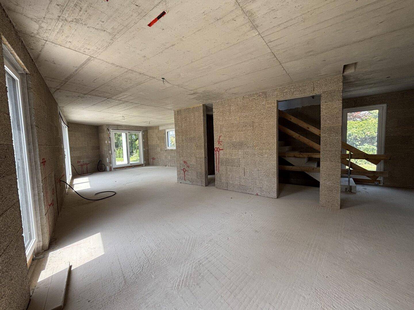 Geräumiger Rohbau mit unverputzten Wänden und Betondecke, bereit für den Innenausbau und lichtdurchflutet.