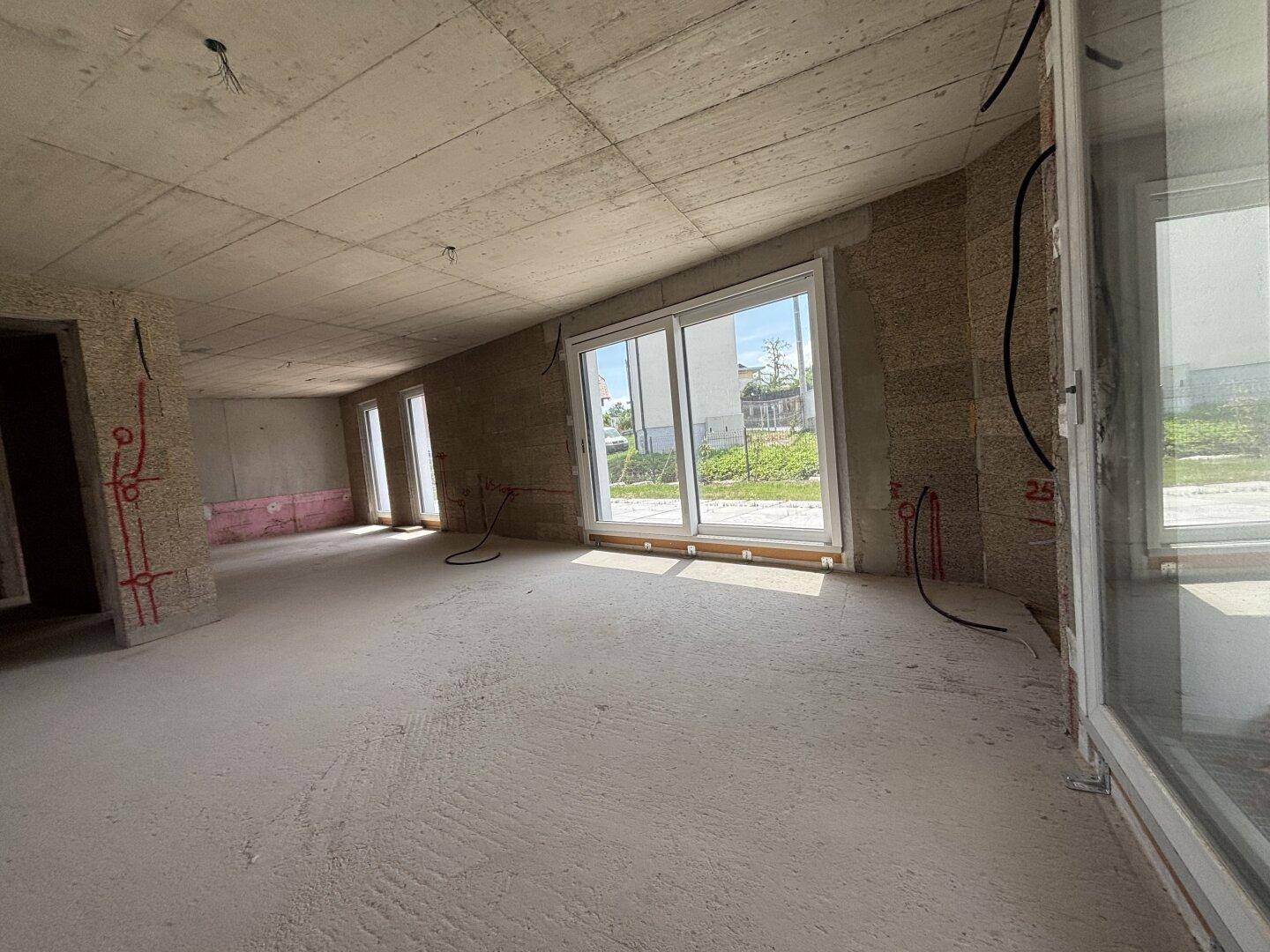 Heller Rohbau mit großer Schiebetür, die viel Tageslicht hereinlässt und Zugang zur Terrasse bietet.