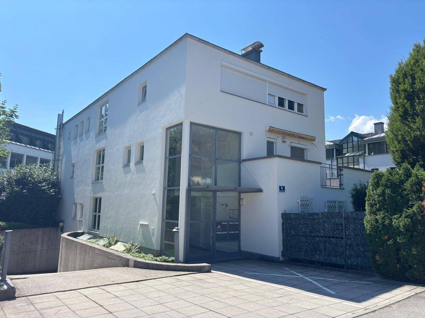 Moderne Gebäudefassade mit großzügigem Eingangsbereich und Zufahrt zur Tiefgarage.