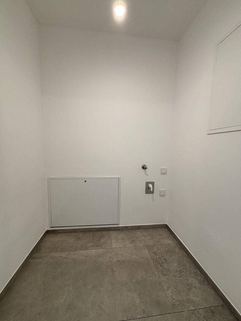 Praktischer Hauswirtschaftsraum mit Fliesenboden und Anschlüssen für Waschmaschine und Trockner.