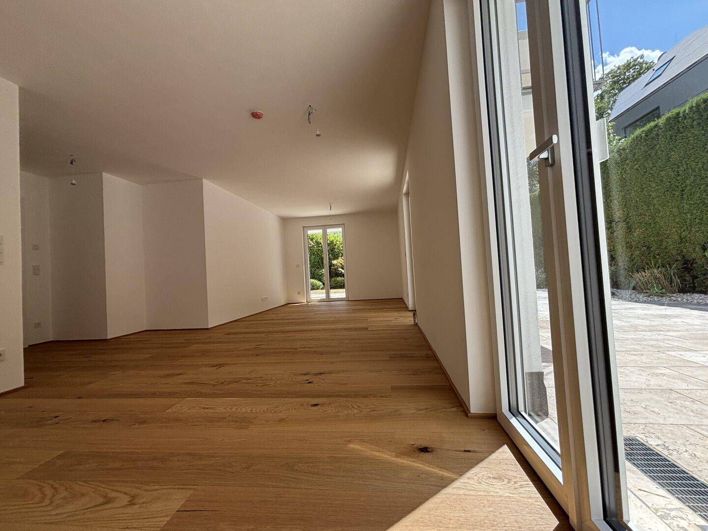 Lichtdurchfluteter Wohnbereich mit Eichenparkett und großen Schiebetüren zur Terrasse.