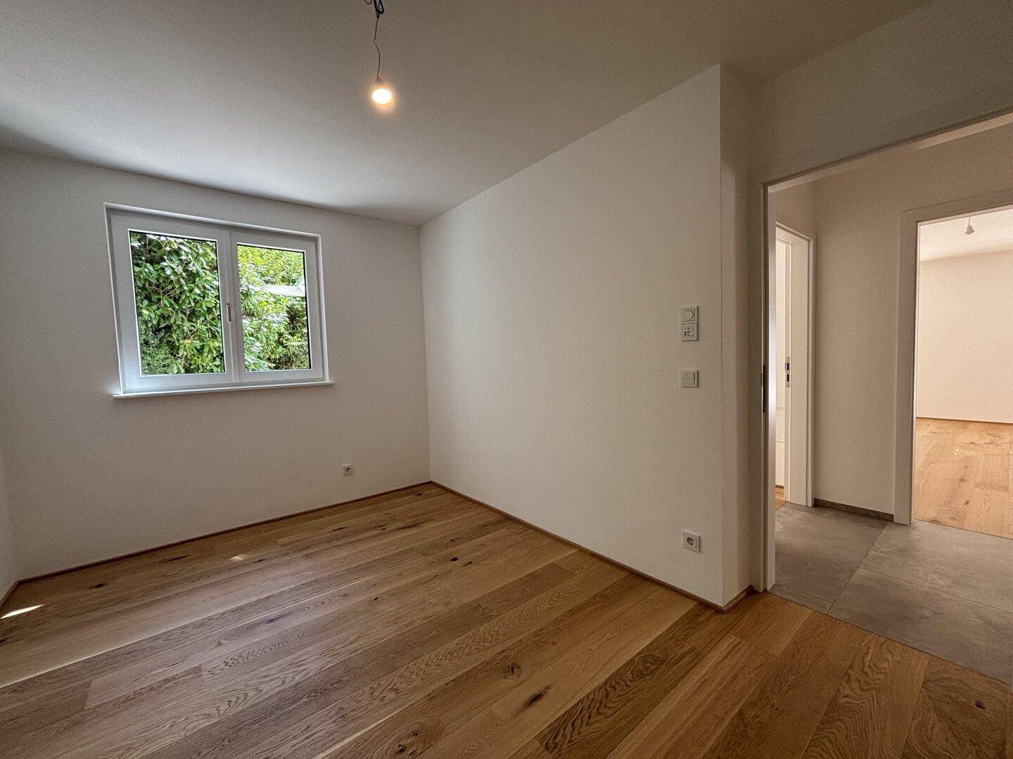 Gemütliches Schlafzimmer mit Eichenparkett und Fenster mit Blick ins Grüne.