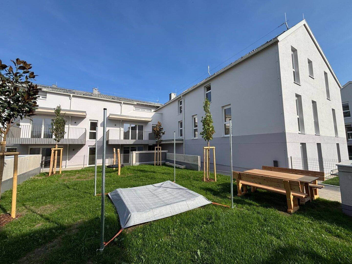 Gemeinschaftliche Grünfläche mit Picknicktisch und Blick auf die moderne Wohnbebauung.