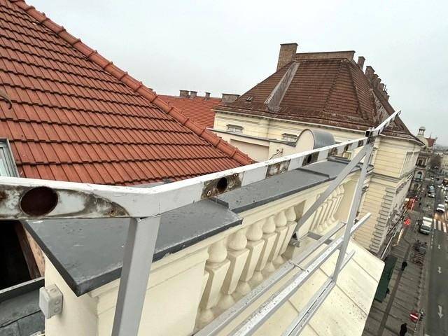Detailansicht des Daches mit roten Ziegeln, Balustrade und Metallgeländer.