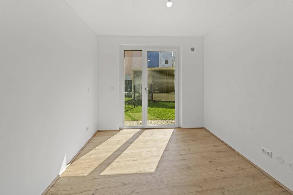 Sonniges Zimmer mit Eichenparkett und großzügiger Schiebetür zum privaten Gartenbereich.