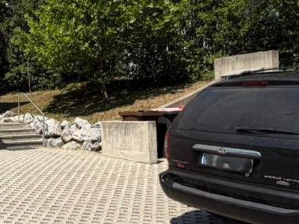 Zufahrt zu einem Tiefgaragenbereich, umgeben von üppigem Grün und Bäumen.