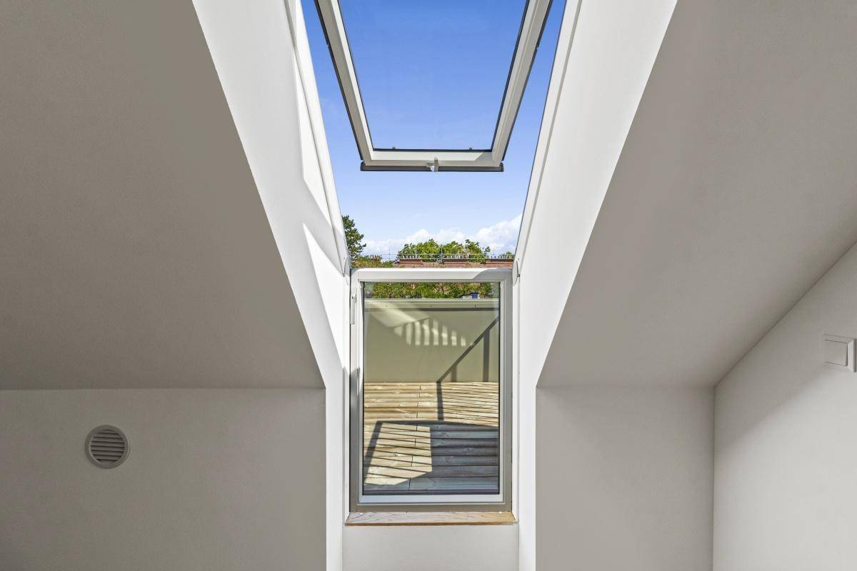 Heller Raum mit Dachschräge und einem großen Dachfenster, das sich nach außen öffnen lässt.
