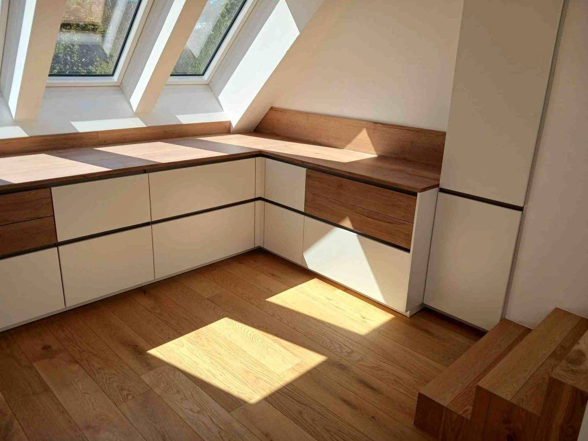 Maßgefertigte Einbauschränke mit Holzfronten und Arbeitsflächen im hellen Dachgeschoss, praktisch und stilvoll.