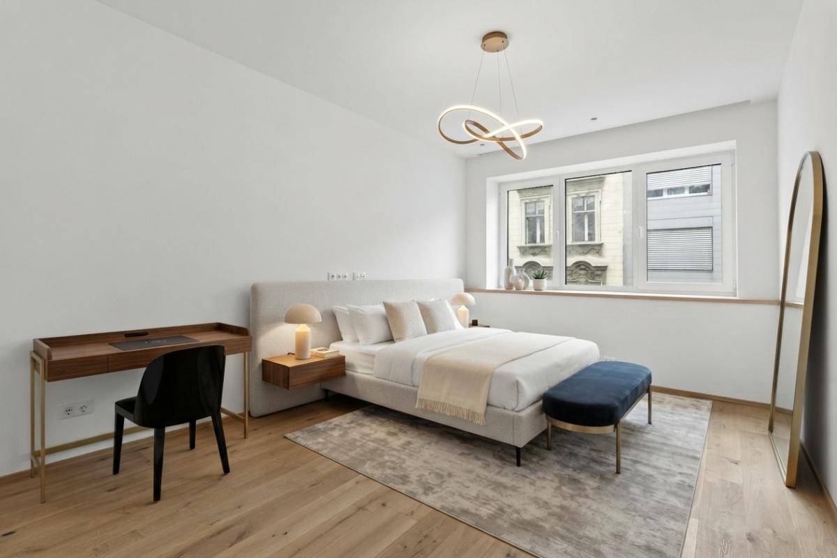 Helles Schlafzimmer mit Doppelbett, Schreibtisch und stilvoller Beleuchtung, bietet Komfort und Funktionalität.