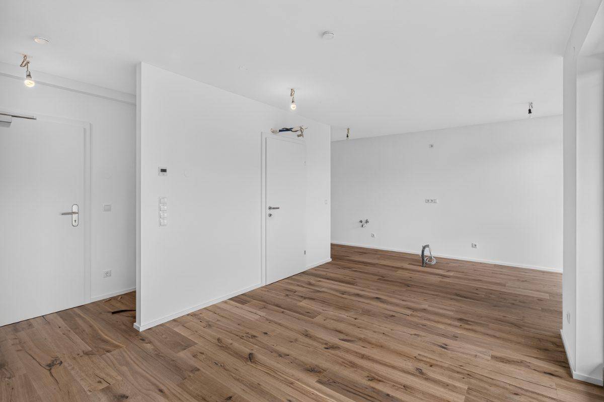 Weiterer Blick in den hellen Raum mit Holzboden und weißen Wänden, bereit zum Einzug.