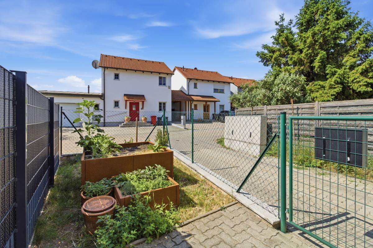 Kleiner Gartenbereich mit Hochbeeten und Zaun, ideal für den Anbau von Kräutern und Gemüse.