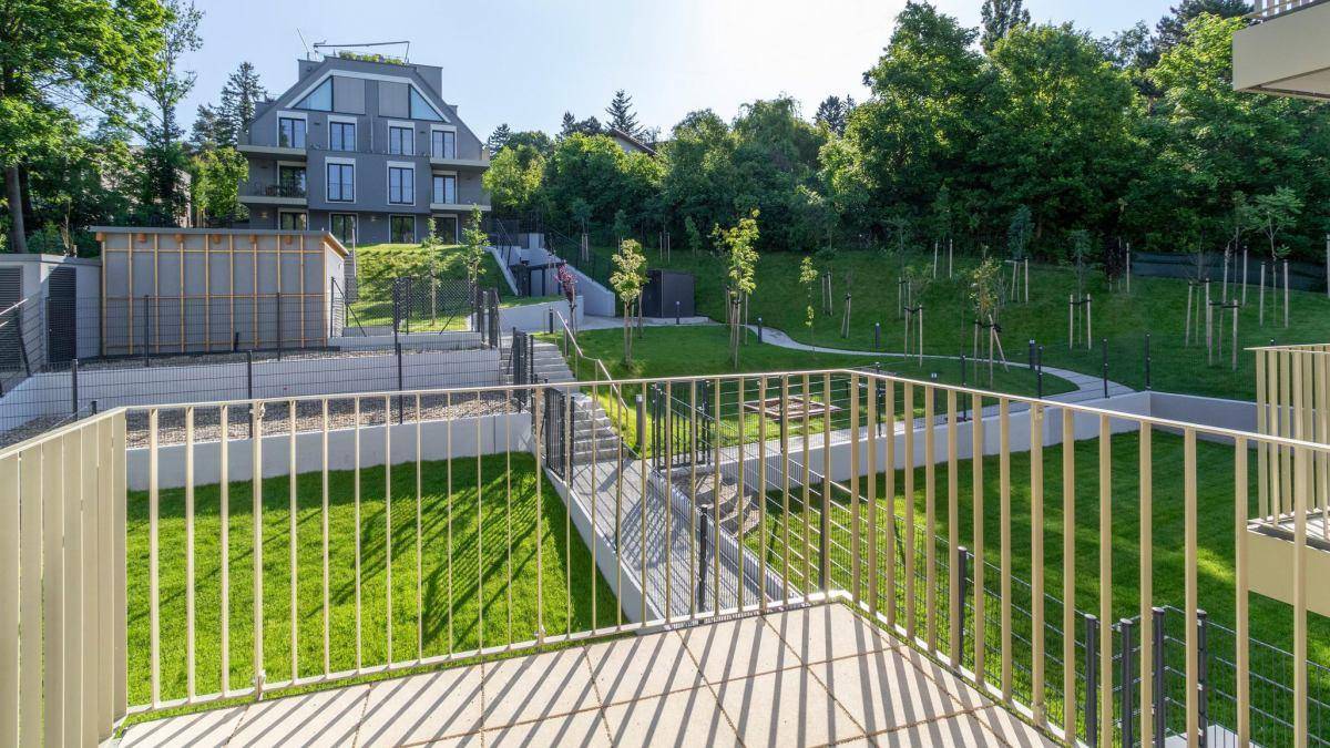 Weitläufige Grünfläche mit Bäumen und Wegen, gesehen von einem Balkon.