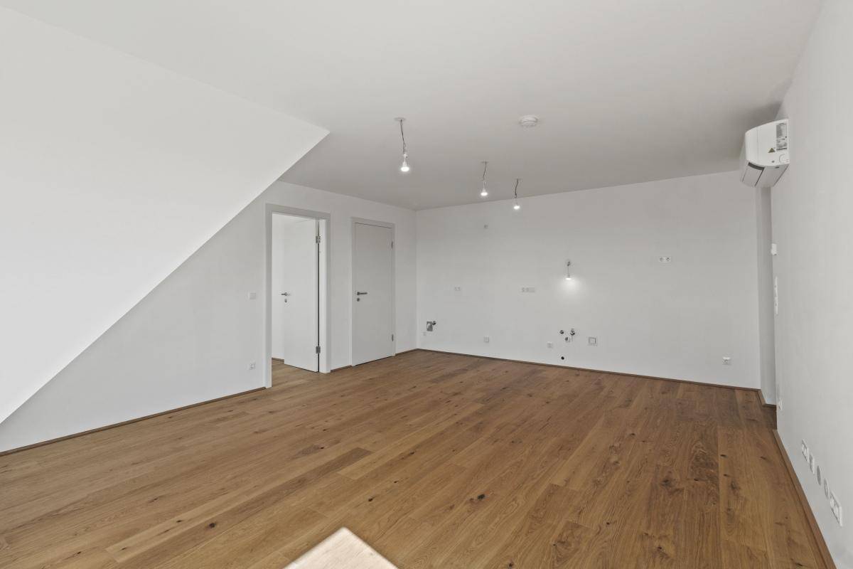 Leerer Raum mit Holzboden und weißen Wänden, bereit für individuelle Gestaltung.