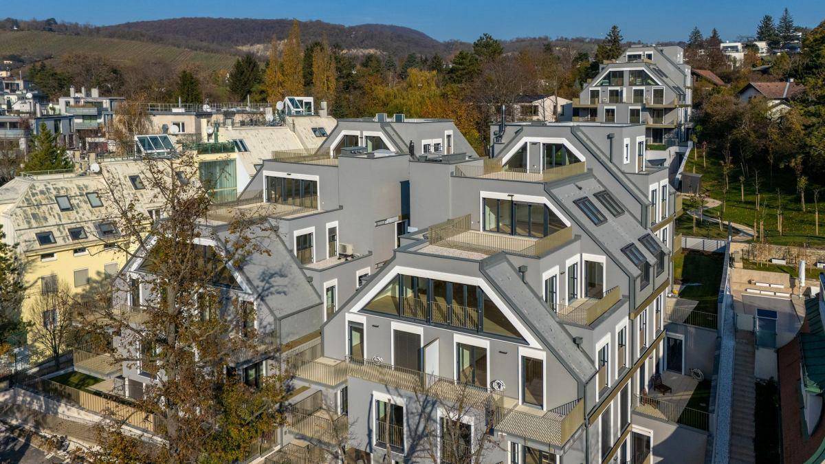 Luftaufnahme einer modernen Wohnanlage mit mehreren Gebäuden und Dachterrassen in grüner Umgebung.