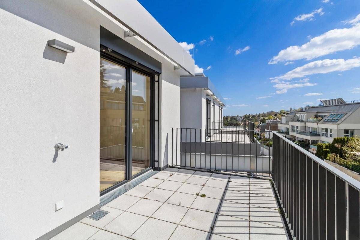 Heller Balkon mit Fliesenboden und Blick auf die umliegenden Gebäude und die Landschaft.