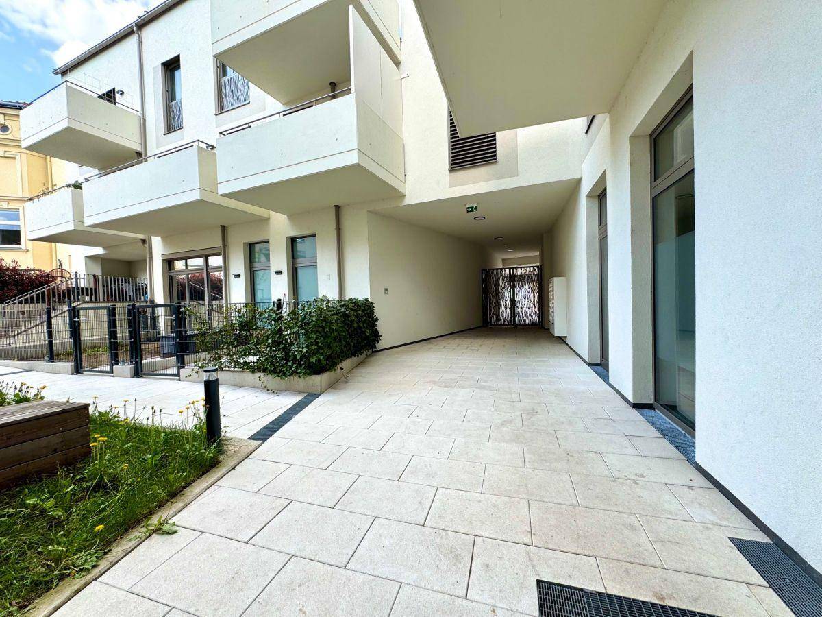 Überdachter Eingangsbereich eines modernen Wohnkomplexes mit hellem Fliesenboden.