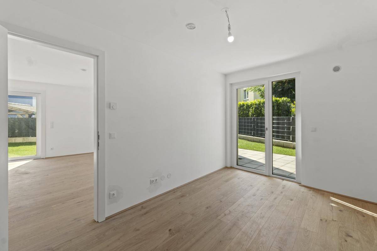 Helles Zimmer mit Parkettboden und Schiebetür, die einen schönen Blick in den Garten bietet.