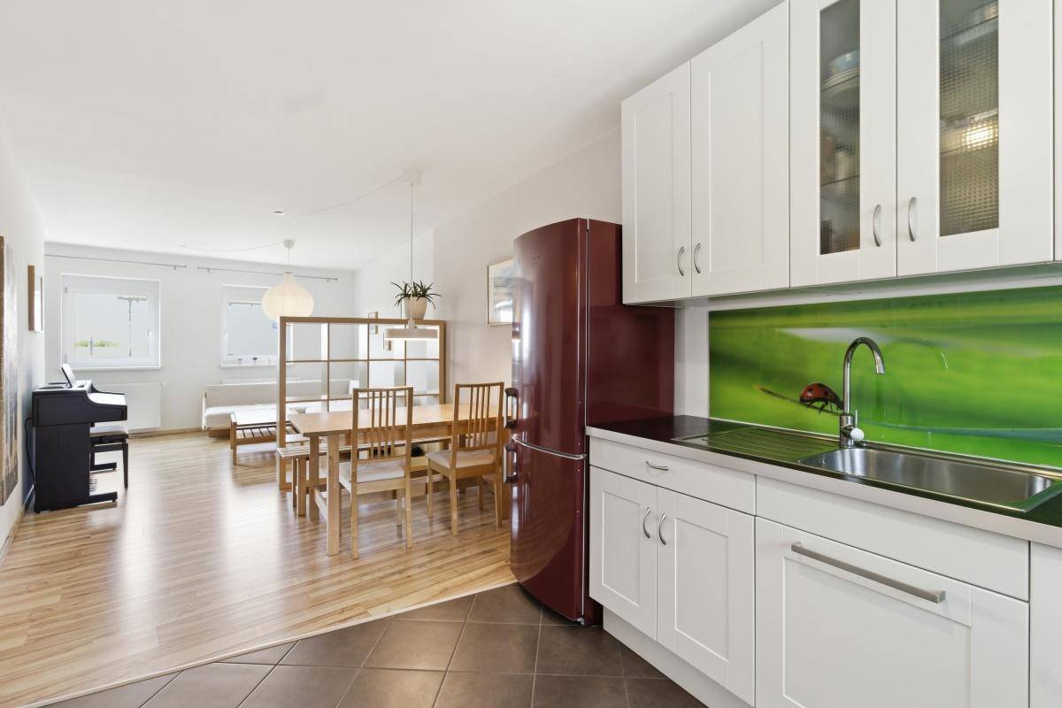 Offene Küche mit Essbereich und Blick in das helle Wohnzimmer, ausgestattet mit Holzboden und modernen Möbeln.