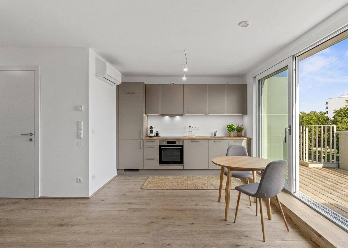 Moderne Einbauküche mit Essbereich, hellen Schränken und direktem Zugang zur großen Terrasse.