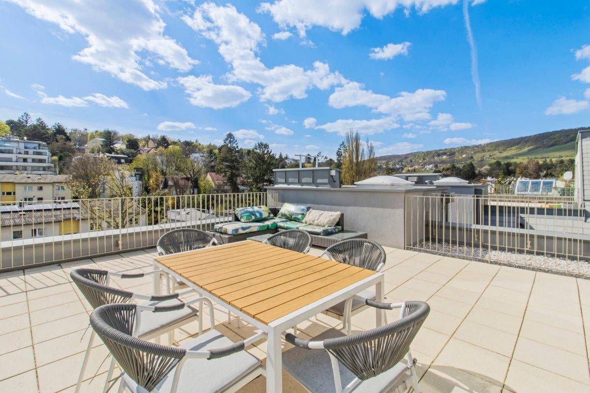 Sonniger Außenbereich auf der Dachterrasse mit Esstisch und Lounge-Sofa.