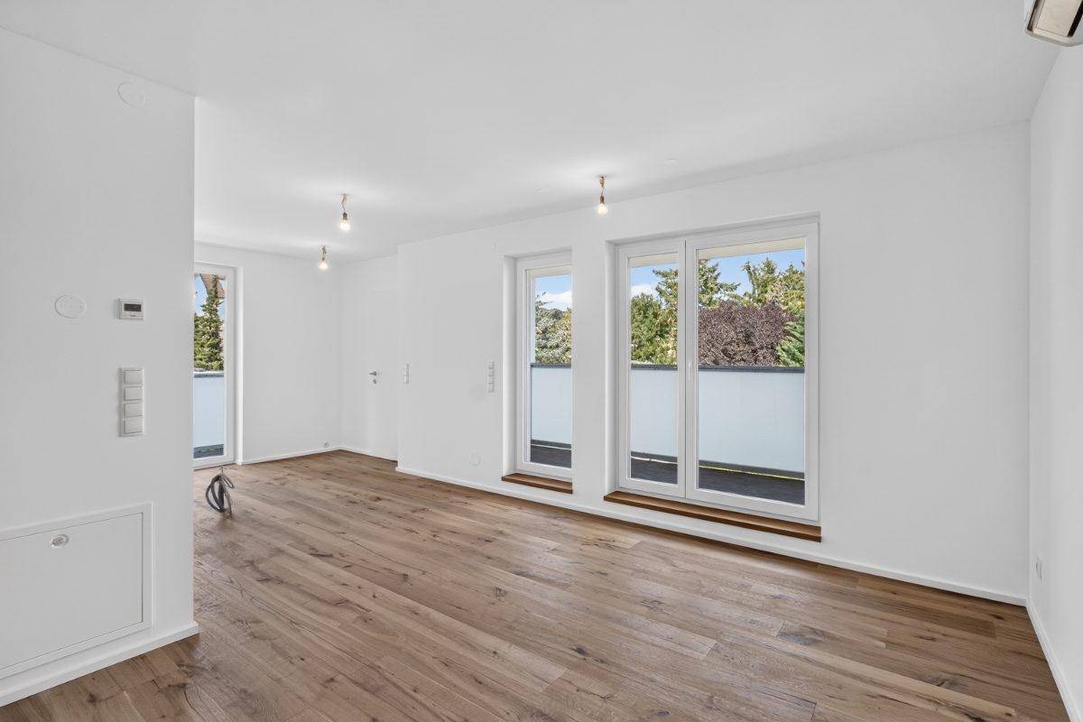 Heller Wohnraum mit Holzboden und Zugang zu einem Balkon, bereit für die Einrichtung.