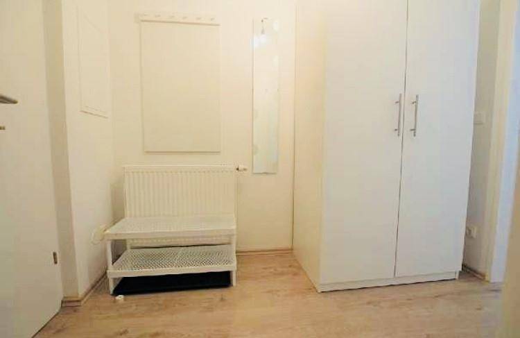 Eingangsbereich mit Garderobe, Heizkörper und weißem Kleiderschrank auf Laminatboden.