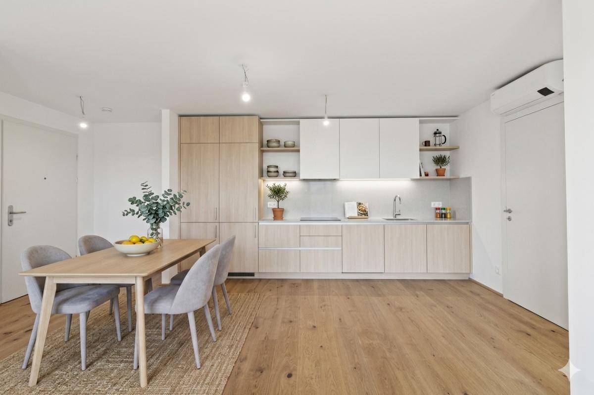 Moderne Einbauküche mit hellem Holz und weißen Fronten, kombiniert mit einem Essbereich.