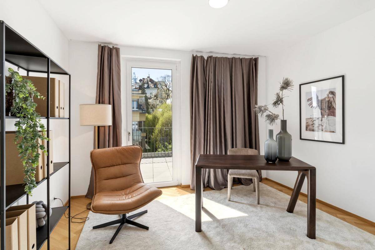 Helles Arbeitszimmer mit Parkettboden, Ledersessel und Zugang zu einem Außenbereich.