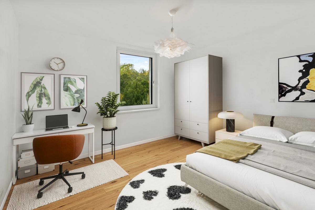 Helles Schlafzimmer mit Schreibtisch, Holzboden und Blick auf Bäume.