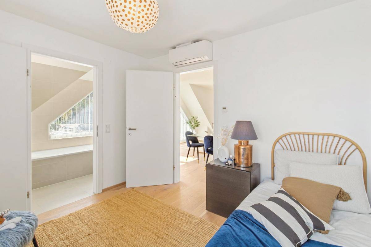 Kinderzimmer mit Holzboden, Dachschräge und Zugang zu einem weiteren Raum.