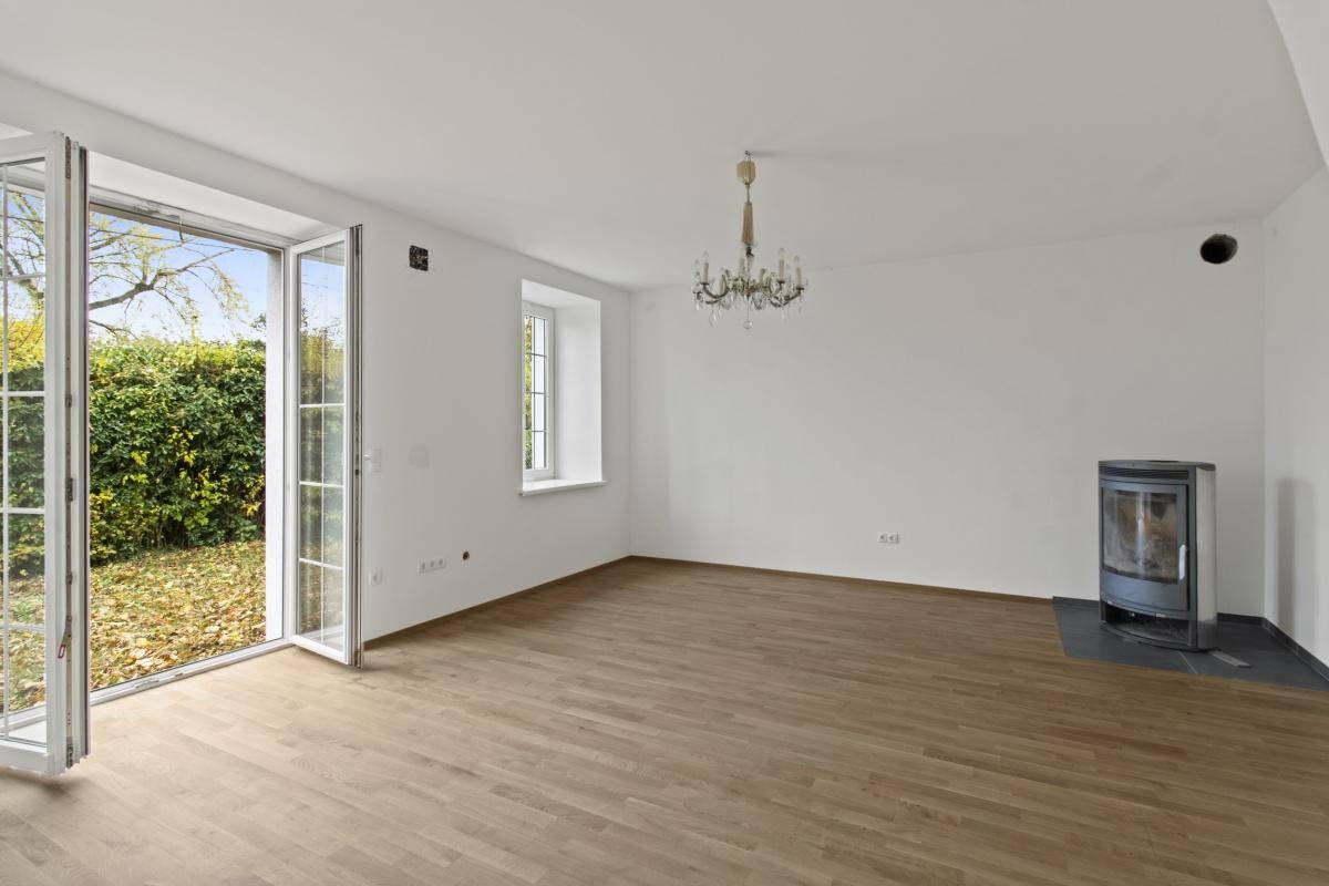 Helles Wohnzimmer mit Holzdielenboden, modernem Kaminofen und französischen Türen zum Garten.