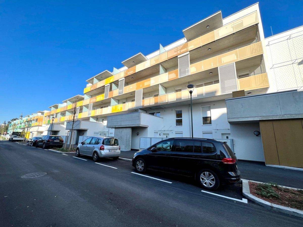 Moderne Wohnanlage mit farbigen Fassadenelementen und Balkonen unter strahlend blauem Himmel.