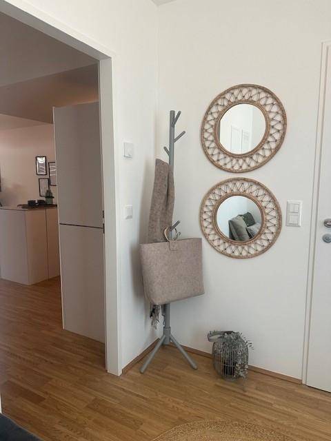 Eingangsbereich mit Holzboden, Garderobe und dekorativen runden Spiegeln an der Wand.