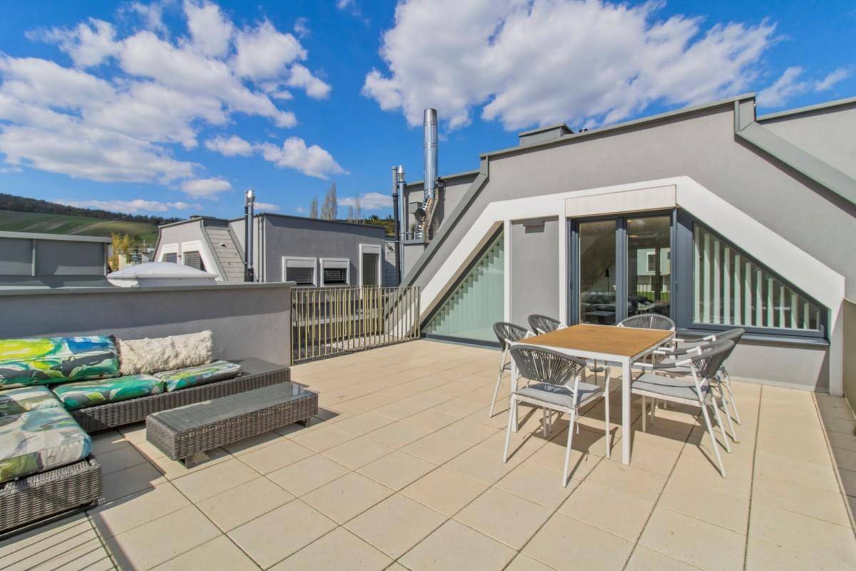 Geräumige Dachterrasse mit modernen Möbeln und Blick auf die umliegenden Gebäude.