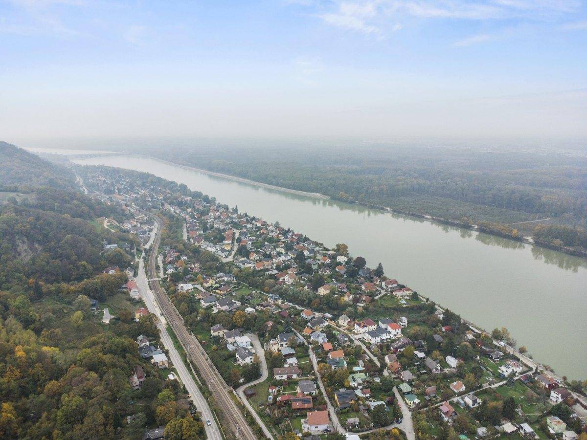 Luftaufnahme der Siedlung entlang des Flusses mit viel Grün und Häusern.
