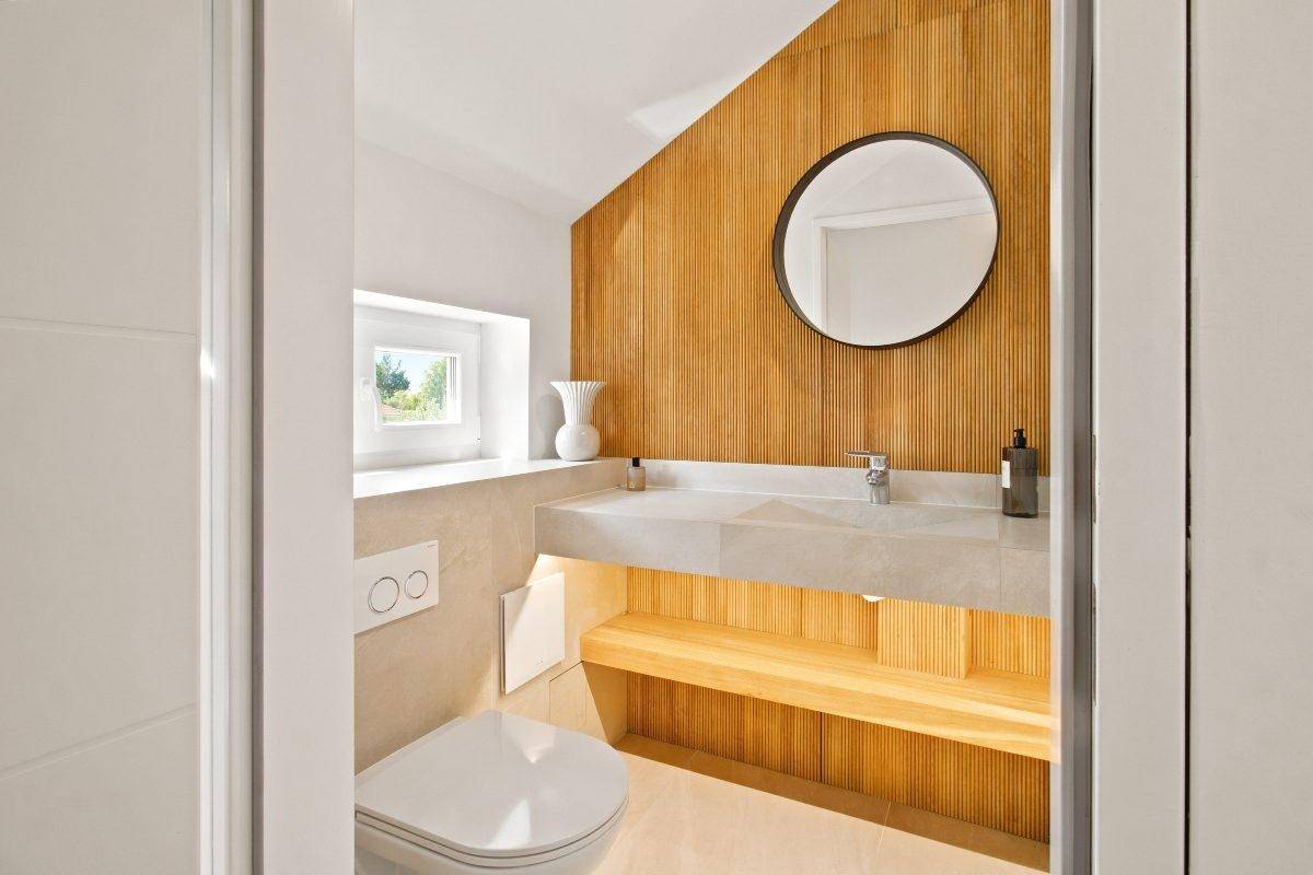 Stilvolles Gäste-WC mit Holzvertäfelung, modernem Waschbecken und Fenster.