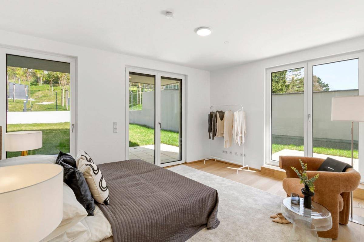 Geräumiges Schlafzimmer mit viel Tageslicht und mehreren Fenstern zum Gartenbereich.