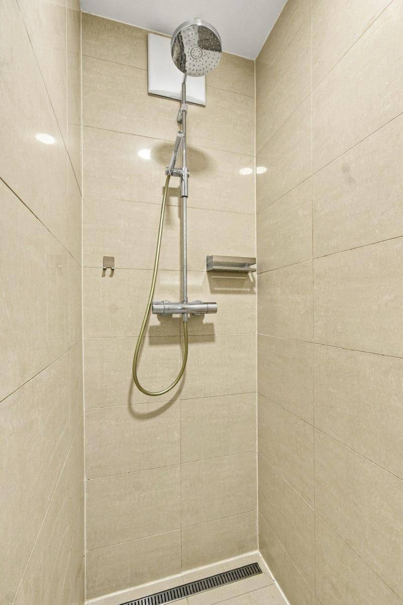 Moderne Duschkabine mit Regendusche und beigen Fliesen.