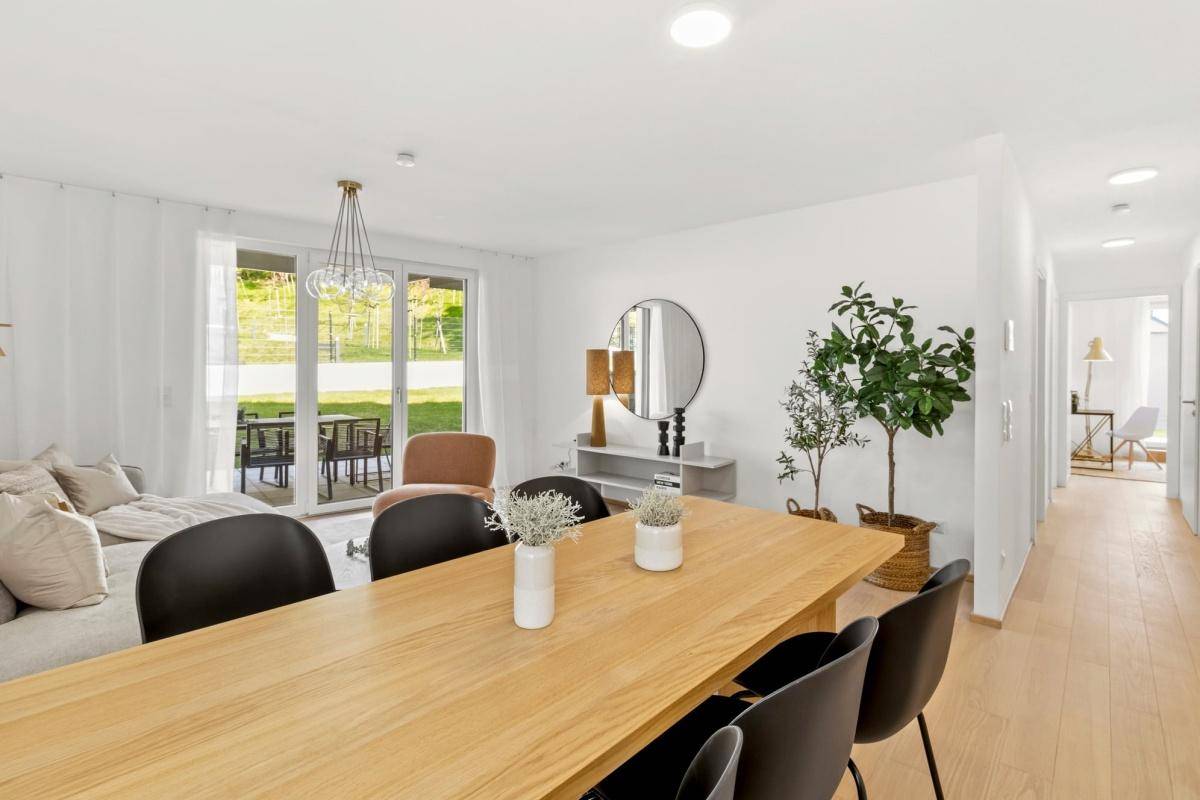 Geräumiger Wohn-Essbereich mit hellem Holzboden und moderner Einrichtung, offen zum Flur.