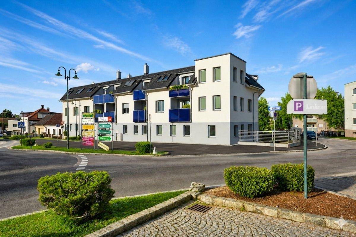 Modernes Wohngebäude mit blauen Balkonen an einer Straßenecke unter blauem Himmel.