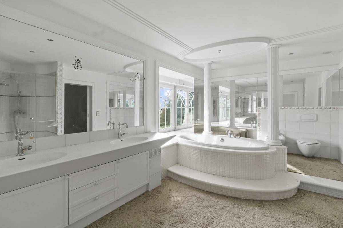 Luxuriöses Badezimmer mit Doppelwaschbecken, großer Badewanne und Spiegelflächen.