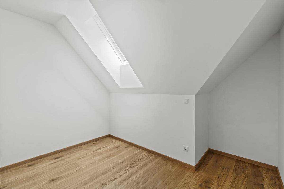 Heller Raum mit Holzboden, Dachschräge und einem Oberlichtfenster, vielseitig nutzbar.