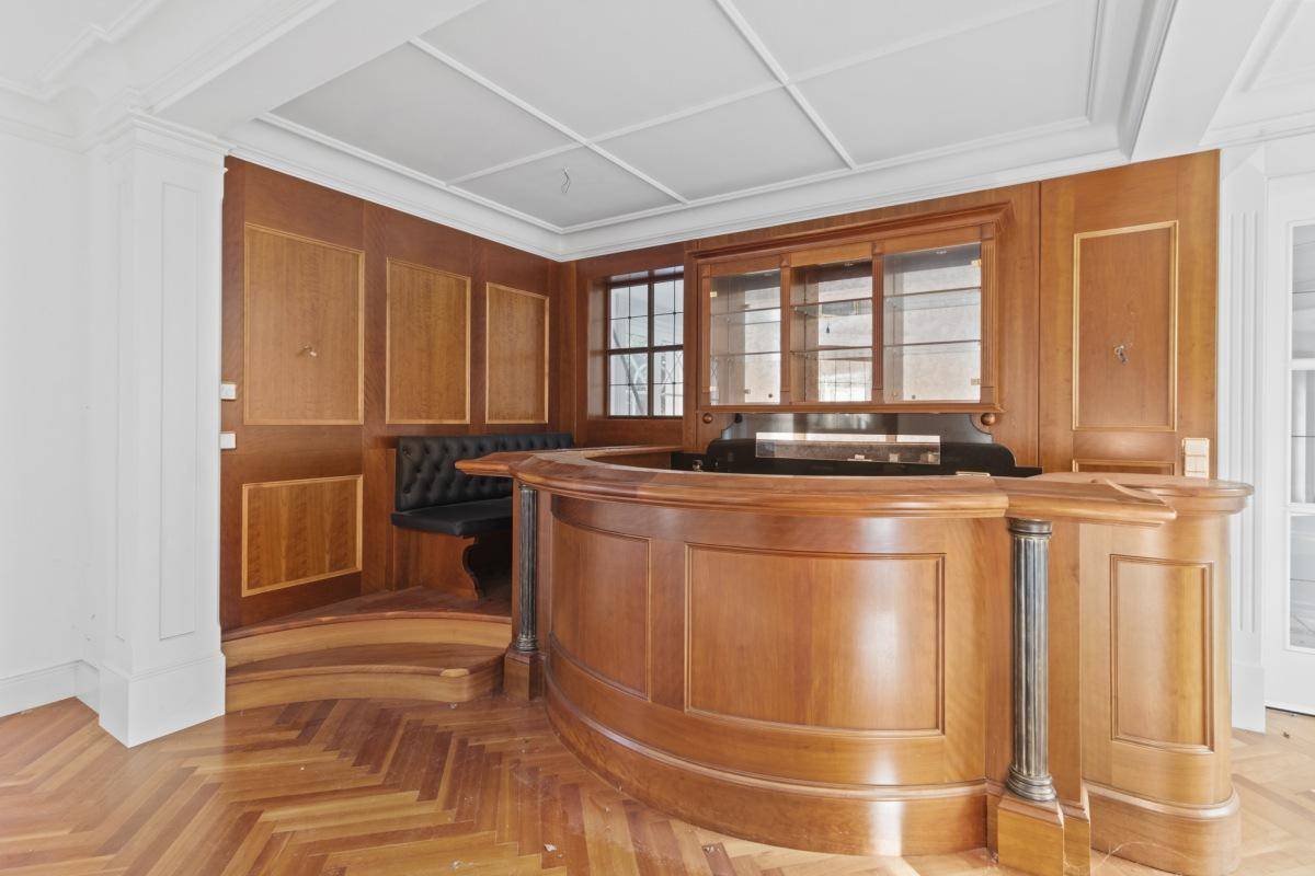 Detailansicht der eleganten Holzbar mit integrierten Sitzgelegenheiten und Vitrinen im Wohnbereich.