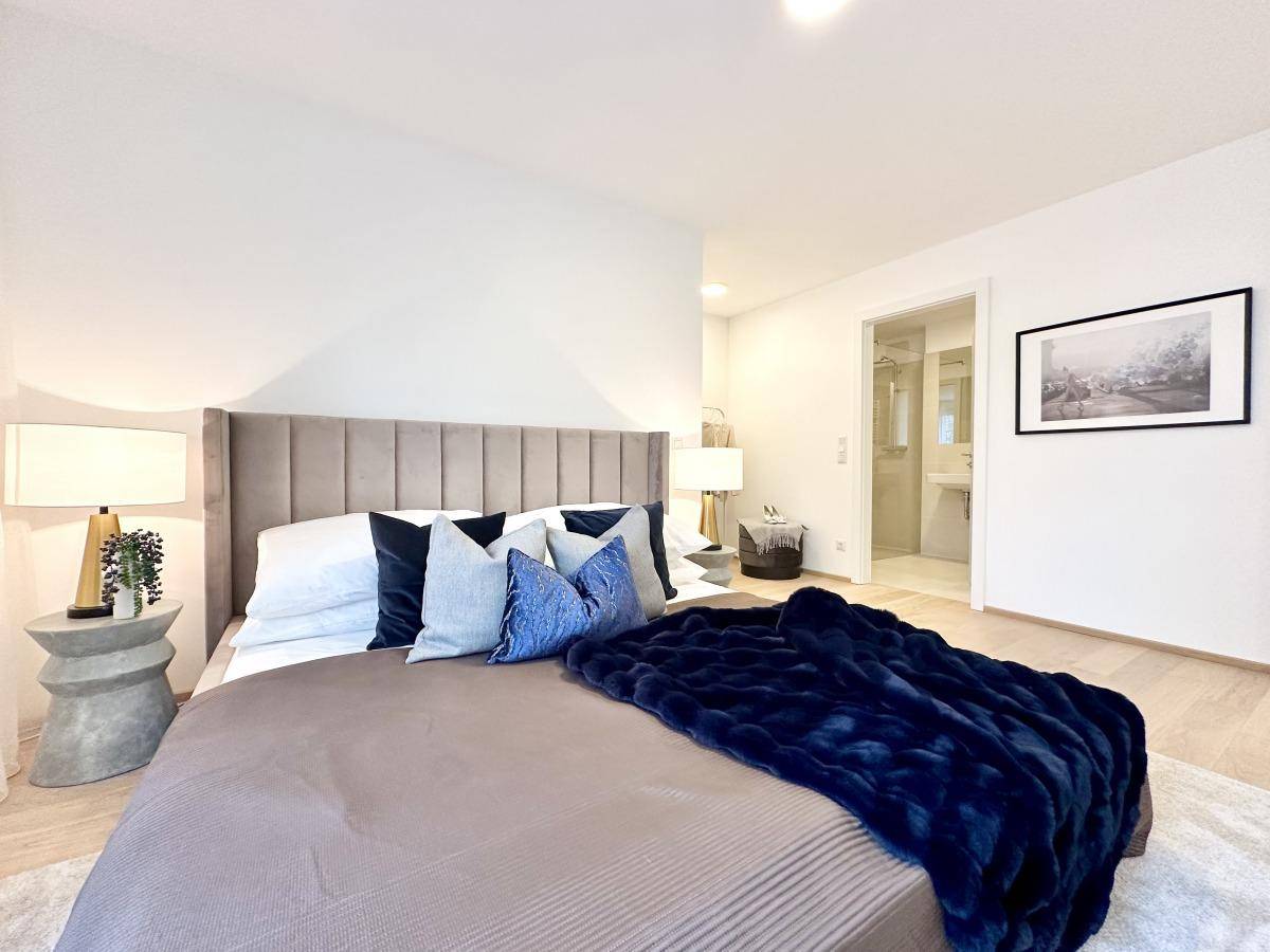 Elegantes Schlafzimmer mit großem Bett, stilvollen Nachttischen und Zugang zum Badezimmer.