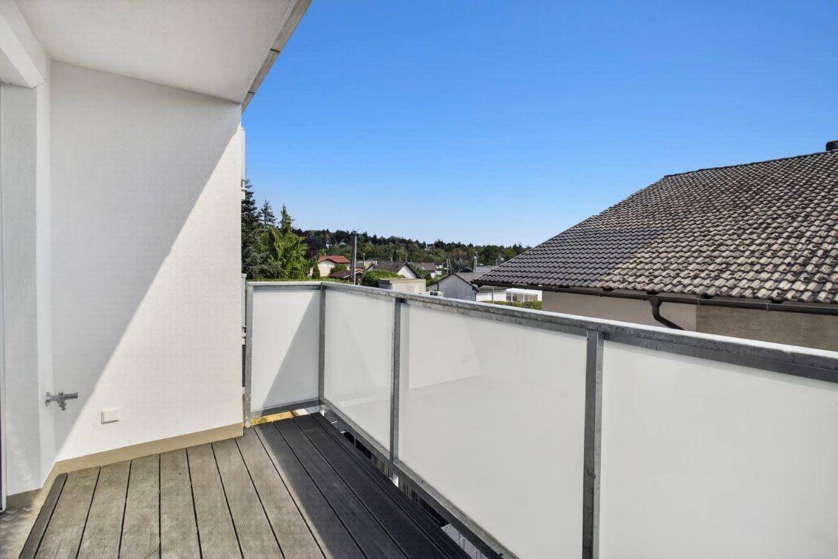 Geräumiger Balkon mit Holzboden und moderner Verglasung, ideal zum Entspannen.