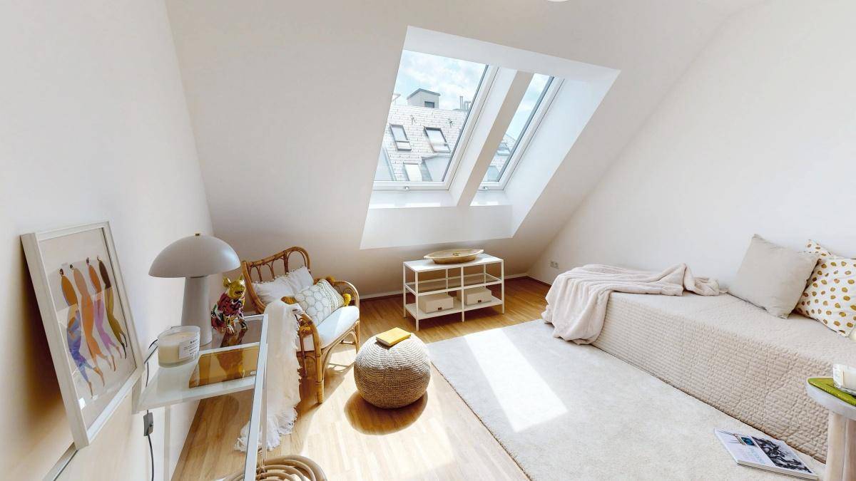 Helles Schlafzimmer mit Dachschrägen, Dachfenstern und minimalistischer Einrichtung.