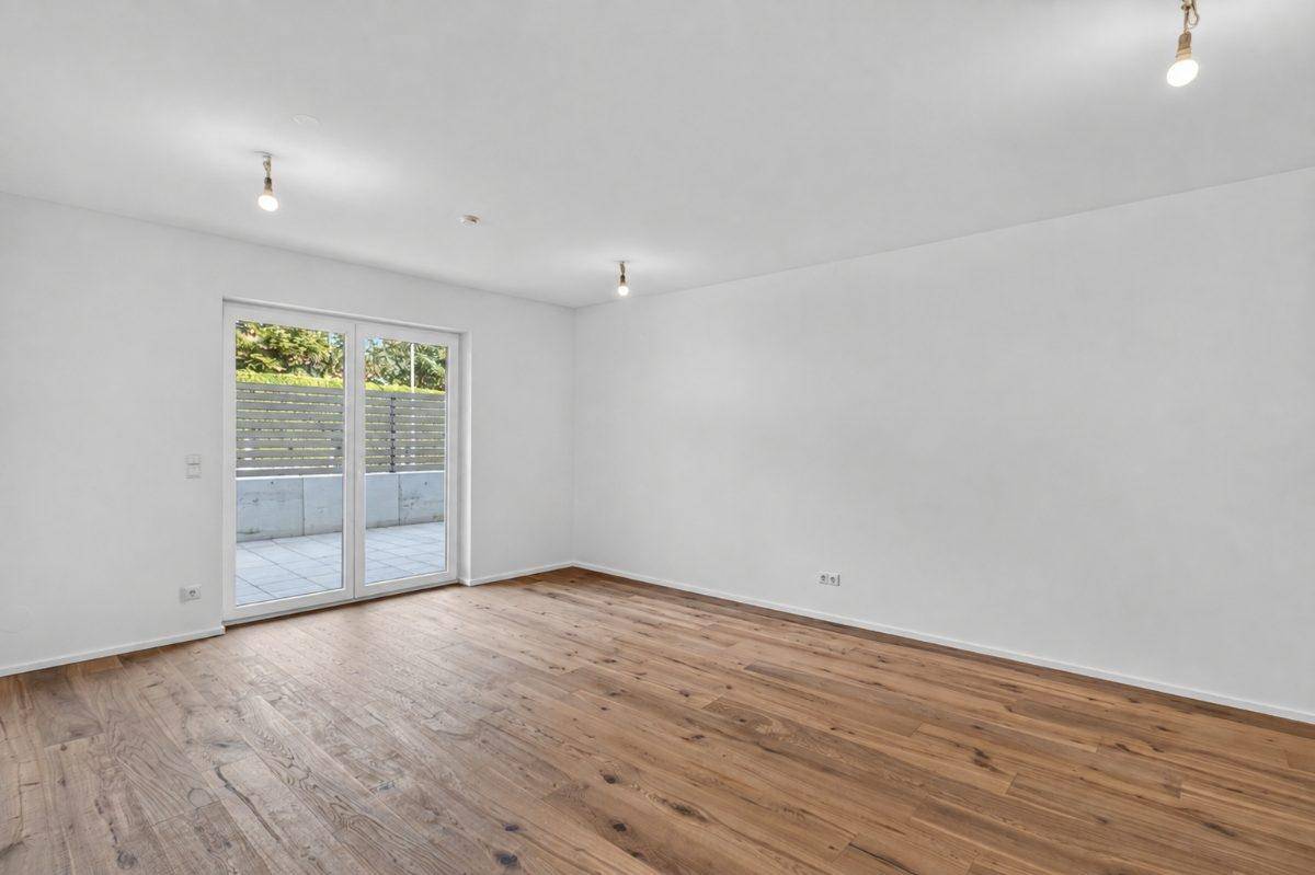 Geräumiges Wohnzimmer mit Holzboden und Zugang zur Terrasse, bereit zur Einrichtung.